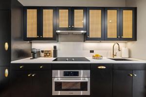 een keuken met zwarte kasten en roestvrijstalen apparatuur bij Freeman 1201 by Rove Studio with Shared Amenities in New York