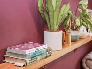 a stack of books sitting on a shelf with plants at 14 Old Market Place in Bonnyrigg