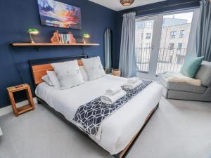 a bedroom with a large bed and a chair at 14 Old Market Place in Bonnyrigg