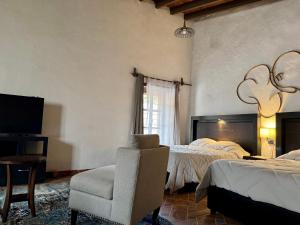 ein Schlafzimmer mit 2 Betten, einem Stuhl und einem TV in der Unterkunft Galera centro de Tepoztlan in Tepoztlán