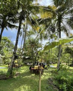 a group of people sitting at tables under palm trees at Villa Claudia Nimal's kitchen in Ahangama