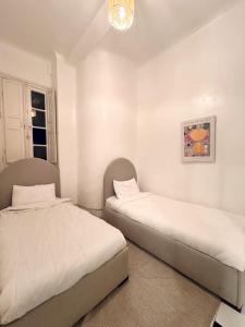 two beds in a room with white walls at Charming apartment heart of Medina 2 min Royal Palace Tetouan 2BR, Balcony in Tetouan