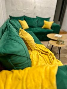 a green couch with yellow pillows in a living room at Industrial Hostel Vila Jovana in Odžaci
