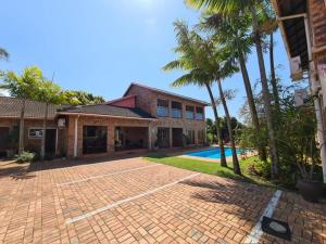 a house with a brick driveway and palm trees at DuneSide Guesthouse in Richards Bay