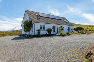 ein weißes Haus mit einer Kiesauffahrt in der Unterkunft Burnside Cottage & Caravan Woodend in Portree