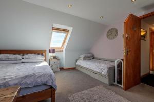 ein Schlafzimmer mit 2 Betten und einer Uhr an der Wand in der Unterkunft Burnside Cottage & Caravan Woodend in Portree + 3 Fotos