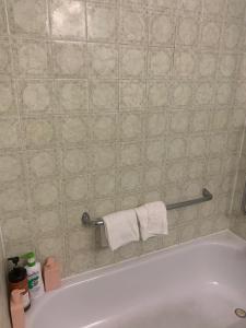 een wit bad met handdoeken op een betegelde muur bij Napaeno's Place - Home Away from Home in Kingston