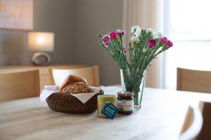 a table with a vase of flowers and a basket of bread at Inselhuus Fehmarn 2 in Petersdorf auf Fehmarn +21 photos
