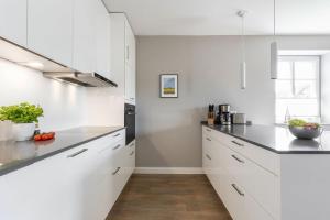 a white kitchen with white cabinets and black counter tops at Inselhuus Fehmarn 1 in Petersdorf auf Fehmarn