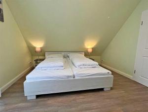 a bed in a room with two lamps on two tables at Meiereikoppel 11 in Petersdorf auf Fehmarn