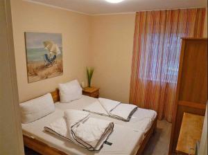 a bedroom with a bed with white sheets and a window at Haus Wellenkamp in Burg auf Fehmarn