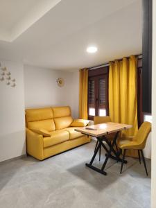 a living room with a yellow couch and a table at Raíces de Alcalá in Alcalá del Júcar