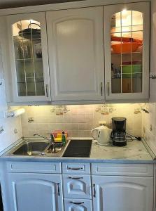 une cuisine avec des armoires blanches et un évier dans l'établissement OASE in Burgtiefe, à Burgtiefe auf Fehmarn 