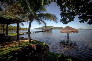 a view of a body of water with a straw umbrella at Rancho Flamboyant Lazer in Lajeado