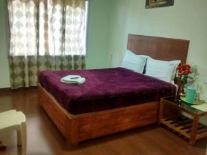 a bedroom with a large bed with a purple comforter at Life style home stay in Kodaikānāl +2 photos