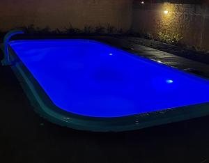 a blue swimming pool in the dark at night at Pousada Toca da Coruja Chales pequeno in Balneário Gaivotas +2 photos