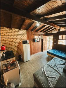 a kitchen with a refrigerator and a bed in a room at Pousada Toca da Coruja Chales pequeno in Balneário Gaivotas
