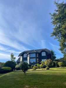 a house with a black roof on a green lawn at Beautiful Plot Lake and Volcano View in Puerto Varas