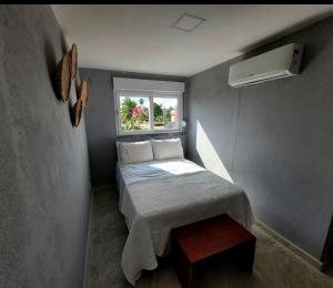 een kleine slaapkamer met een bed en een raam bij rooftop Bellamar in Pôrto de Pedras