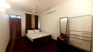 a small bedroom with a bed and a mirror at The Shan Guest House in Nugegoda