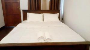 a bed with white sheets and pillows in a room at The Shan Guest House in Nugegoda