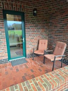 two chairs sitting on a brick patio with a window at Hof Nordholz in Großenkneten