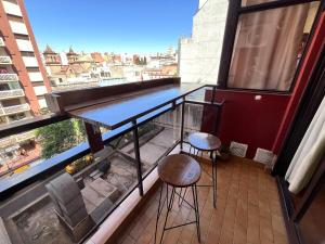 einen Balkon mit einem Tisch und 2 Hockern darauf in der Unterkunft Departamento 1 dormitorio a metros de Patio Olmos in Cordoba