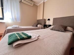 ein Schlafzimmer mit 2 Betten und grünen Handtüchern darauf in der Unterkunft Departamento 1 dormitorio a metros de Patio Olmos in Cordoba