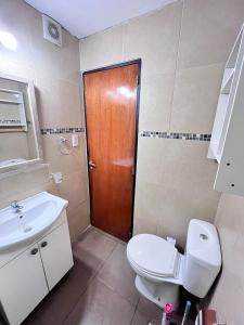 ein Badezimmer mit Toilette und Waschbecken und einer Holztür in der Unterkunft Departamento 1 dormitorio a metros de Patio Olmos in Cordoba + 2 Fotos