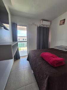 a bedroom with a bed with a red pillow on it at Bangalô duplex 602 - Riviera do Atlântico in Conde