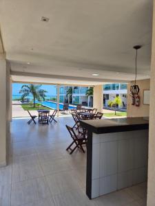 a lobby with tables and chairs and a view of the ocean at Bangalô duplex 602 - Riviera do Atlântico in Conde