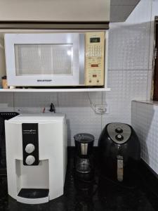 a microwave above a coffee maker in a kitchen at Bangalô duplex 602 - Riviera do Atlântico in Conde
