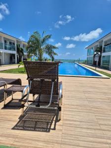 a bench sitting on a boardwalk next to a swimming pool at Bangalô duplex 602 - Riviera do Atlântico in Conde
