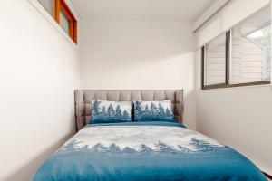 um quarto com uma cama azul e uma janela em Whistler Village Retreat, Private Hot Tub & Sauna em Whistler