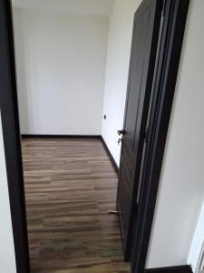 een hal met een zwarte deur en een houten vloer bij kut aguest house in Koetaisi