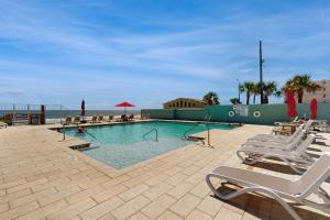 a swimming pool with lounge chairs and the beach at Skyline & Sand in Daytona Beach