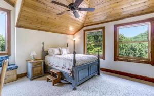 a bedroom with a bed with a ceiling fan and windows at Sunrise to Sunset in Hayesville