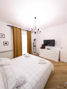 a white bedroom with a bed and a tv at Ai Castelli Apartment - Locazione Turistica CIN IT58060C2FHNREG9A in Colonna +7 photos