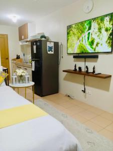 uma cozinha com um frigorífico preto e uma televisão na parede em Norman Condominium Unit Rental em Dumaguete