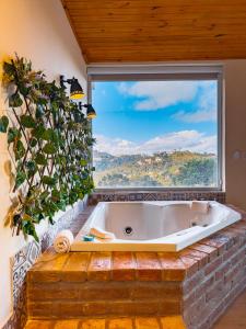 a bath tub in a room with a large window at Pousada Ville Le Mont - Campos do Jordao in Campos do Jordão