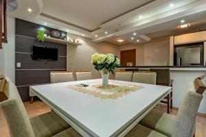 a dining room with a table with a vase of flowers on it at Imóvel bem localizado em Canela, cobertura in Canela