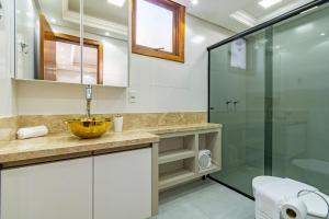 a bathroom with a sink and a glass shower at Imóvel bem localizado em Canela, cobertura in Canela +23 photos