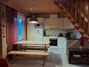 a kitchen with white cabinets and a table with benches at AnriStar in Äkäslompolo