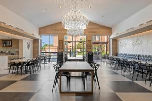 a dining room with tables and chairs and a chandelier at Kompose Boutique Hotel Houston Cy-Fair in Houston