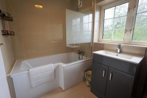 a bathroom with a tub and a sink at Beautiful 2 Bed Home with Spacious Garden in Shephall