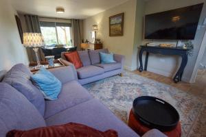 a living room with a purple couch and a tv at Beautiful 2 Bed Home with Spacious Garden in Shephall