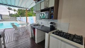 a kitchen with a stove and a deck with a pool at Pousada Bahamas Sc in Penha