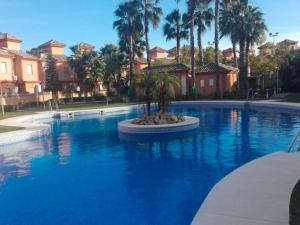 a large swimming pool with a palm tree in the middle at Leisurely Apartment in Lepe with Swimming Pool in La Antilla