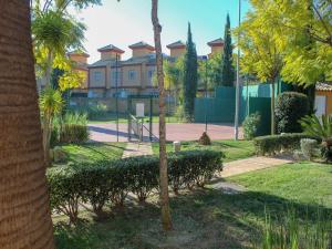 a building in a park with a palm tree at Leisurely Apartment in Lepe with Swimming Pool in La Antilla