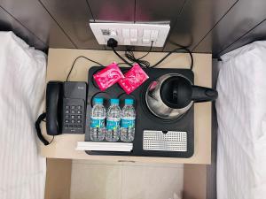Una cama con un teléfono y botellas de agua en un escritorio. en Knight Oasis, en Khātu